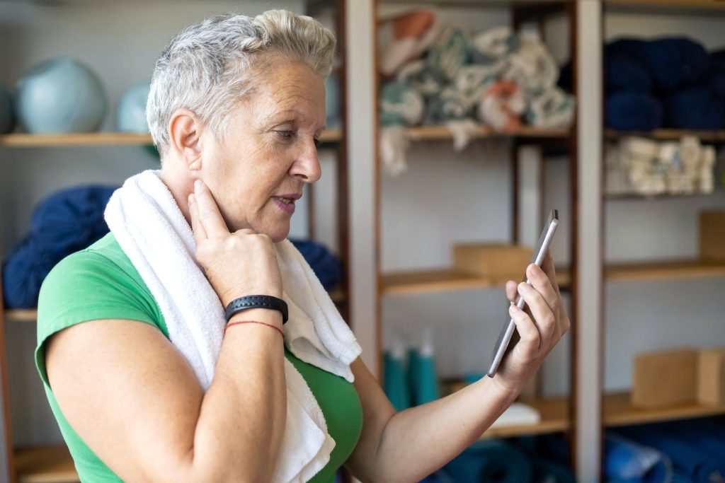 Mujer mayor consultando su plan en el móvil después de entrenar en casa