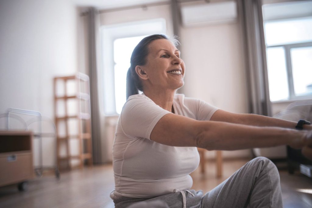 Mujer entrenando en casa con mancuernas, sonriente