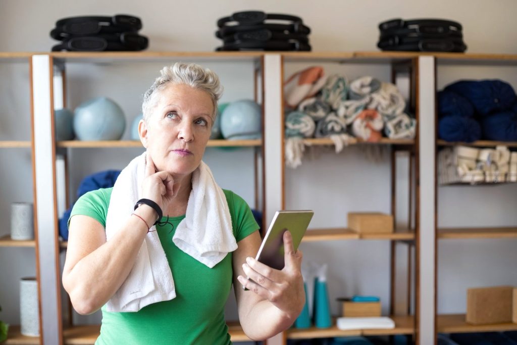 Mujer mayor usando la app en el móvil en su espacio de entrenamiento