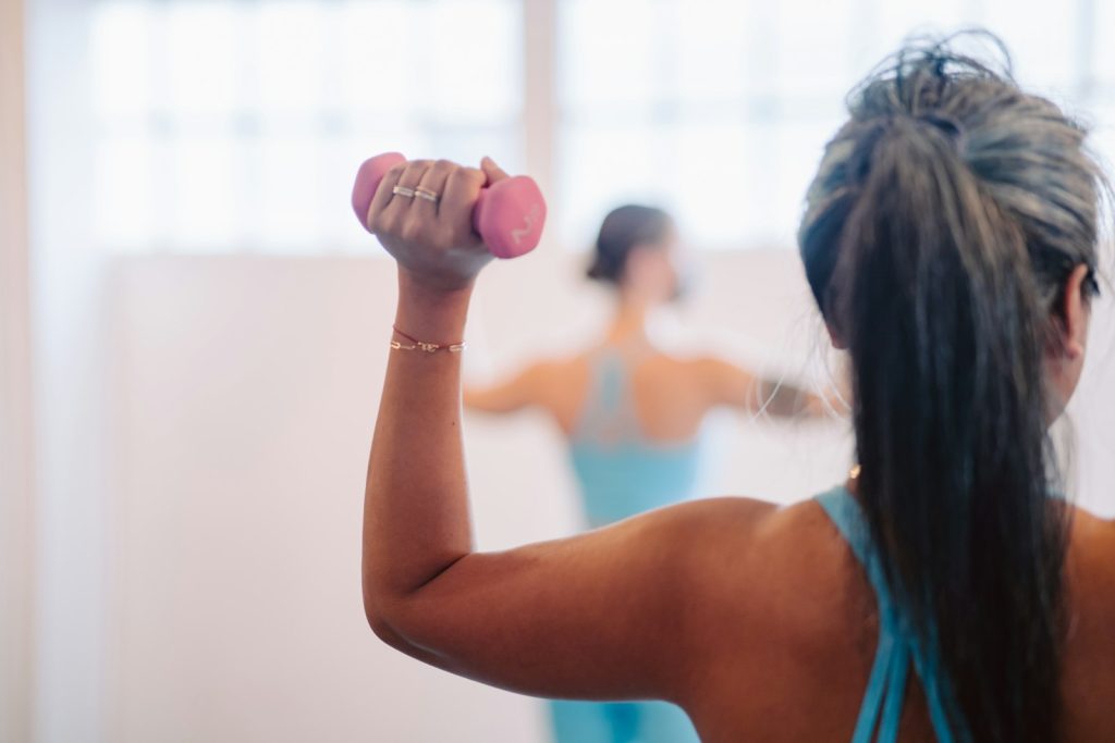 Mujer con canas entrenando la fuerza con mancuernas ligeras